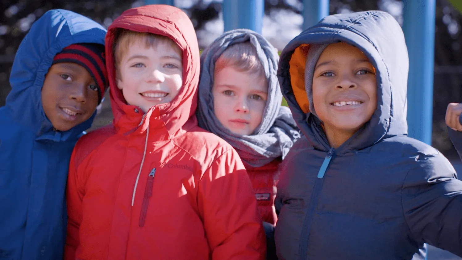 Children in bright raincoats laughing together — a frame from Starting at Zero, the feature documentary directed by Willa Kammerer